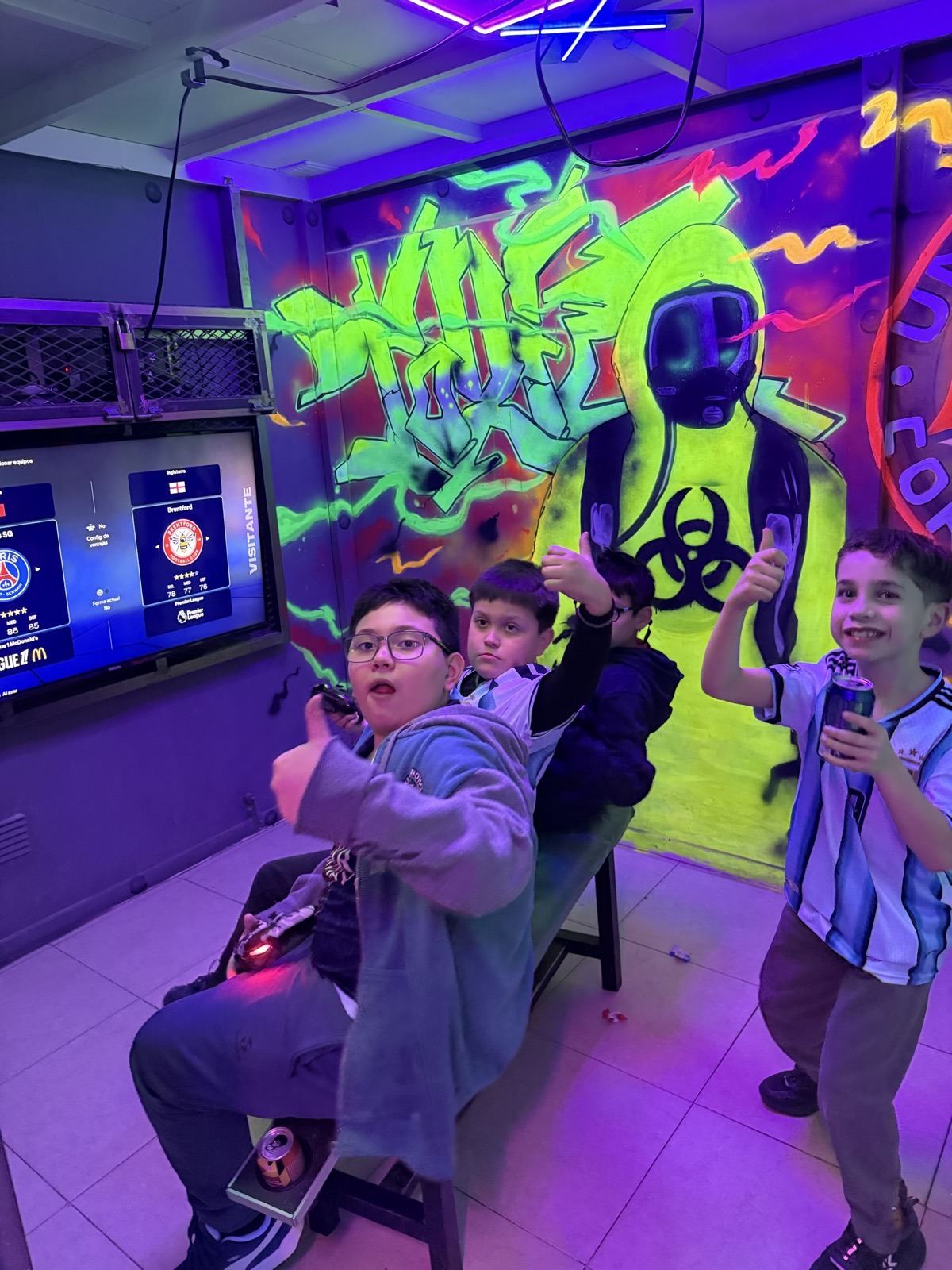 Chicos jugando con joysticks frente a la pared de graffiti