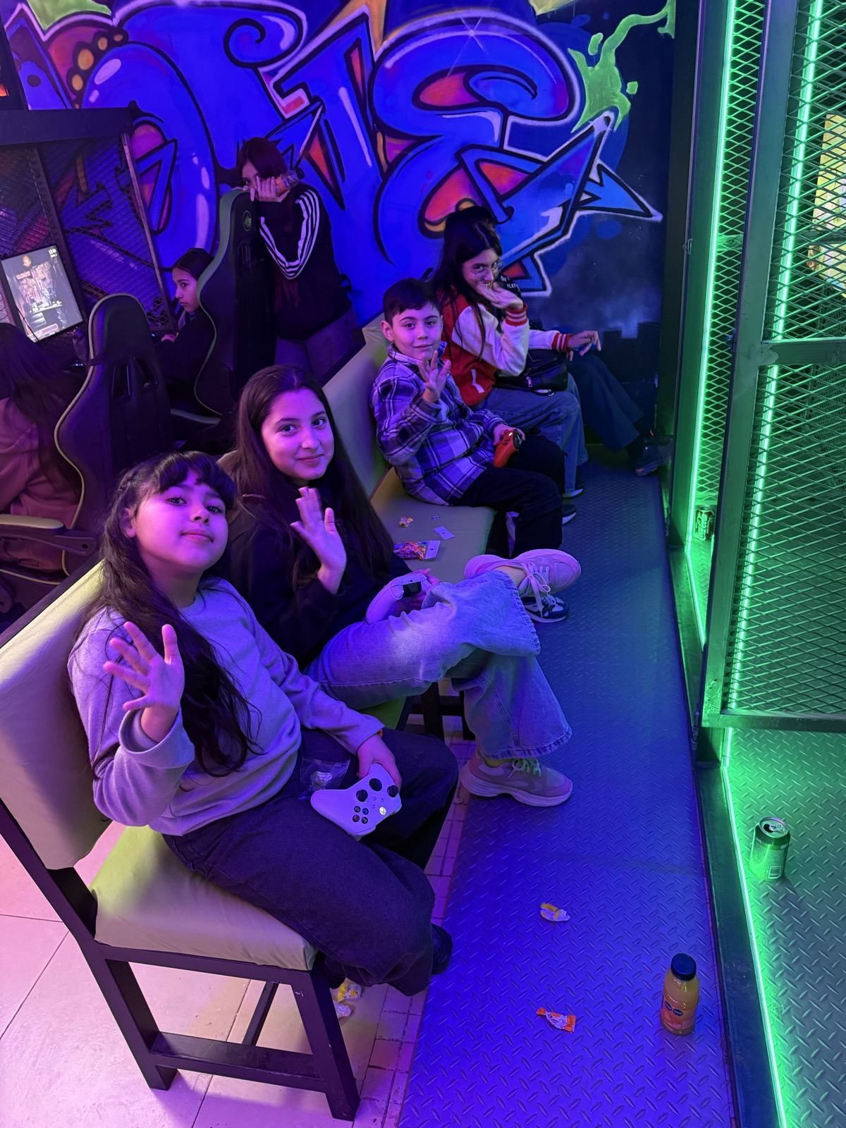 Chicos jugando con joysticks bajo las luces neón